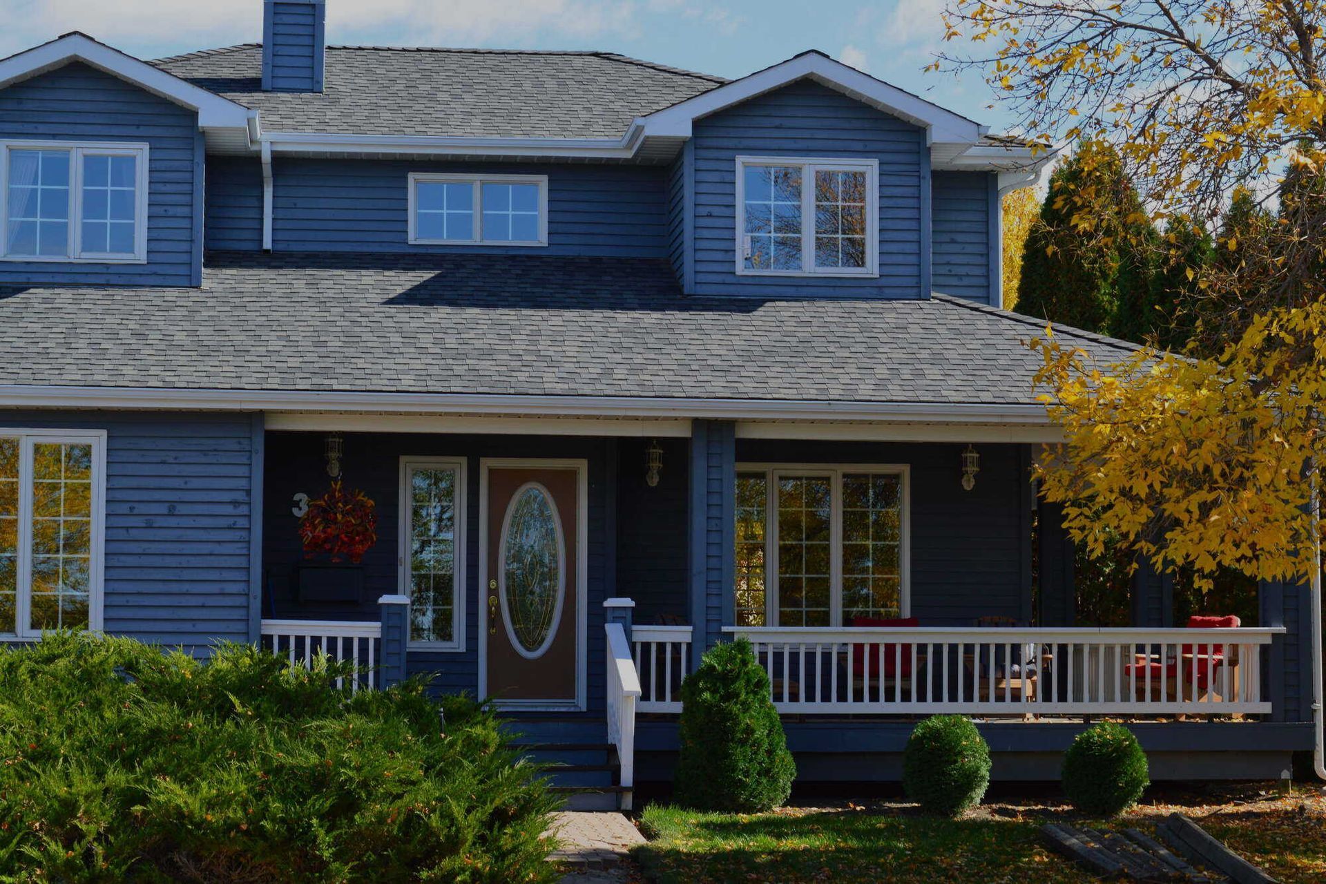 A large blue house with a porch and a lot of windows.