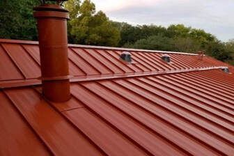 A red metal roof with a chimney on top of it.