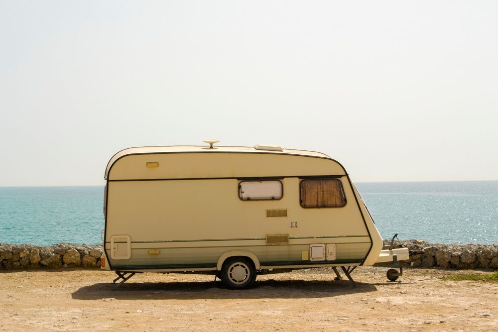 A Caravan is Parked on the Beach Next to the Ocean — Chilltech Air Conditioning & Refrigeration In Rockyview, QLD