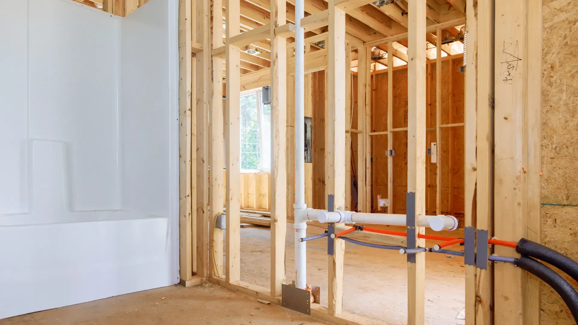 Interior of a building under construction, with wooden framing and plumbing installed.