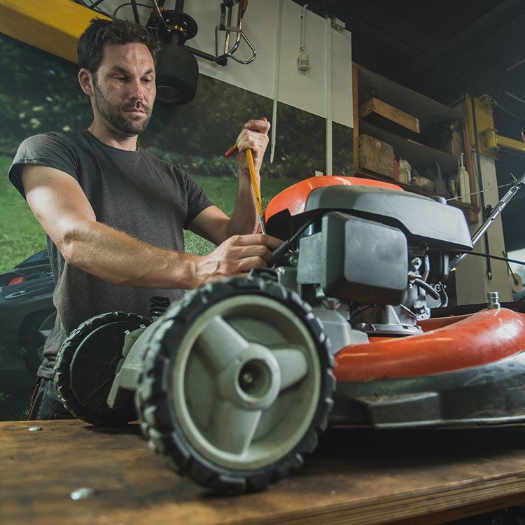 Worker Fixing Lawn Mower — Garden Tool Repairs In Bowen, QLD