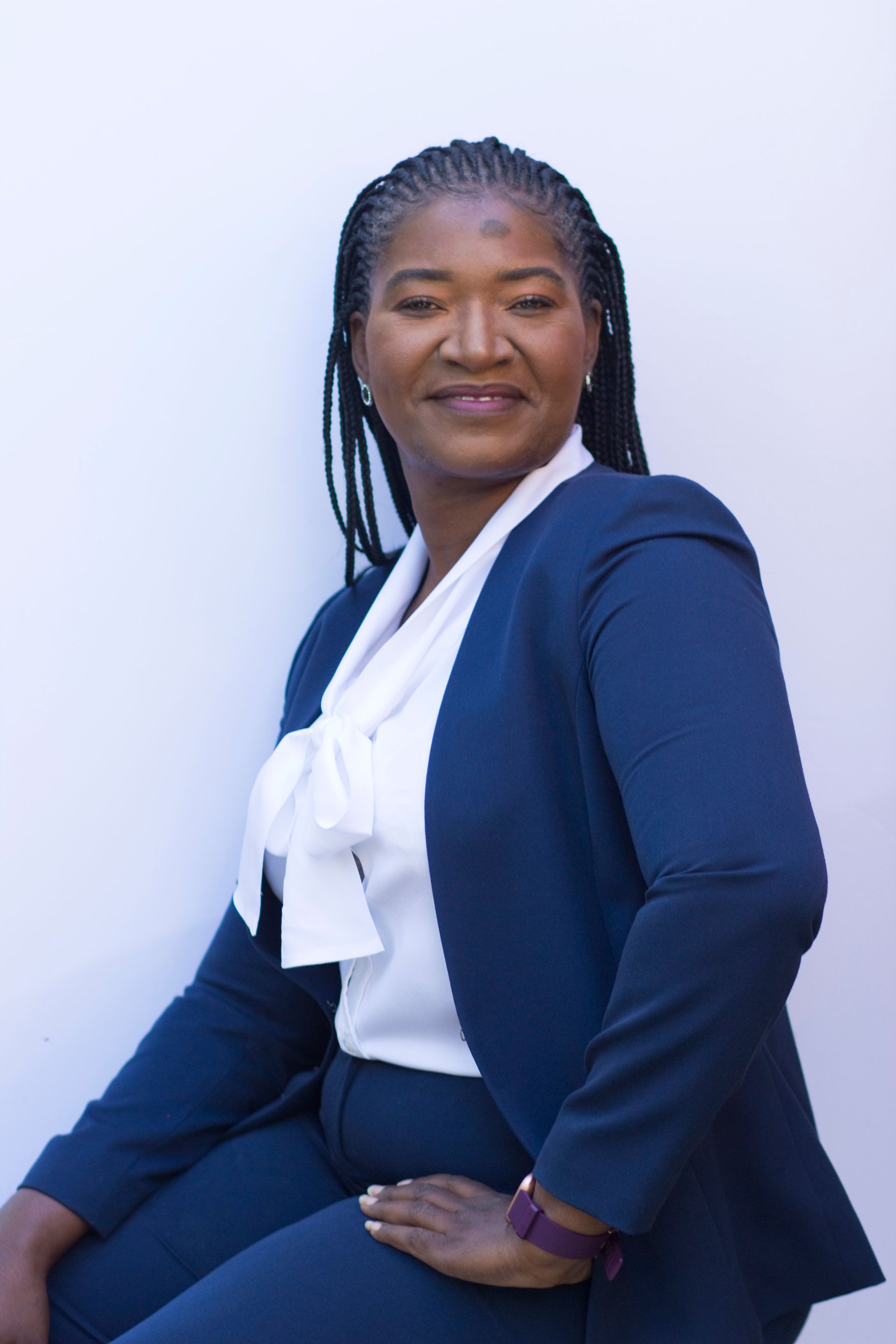 A woman is sitting at a desk with a laptop and a vase of flowers.