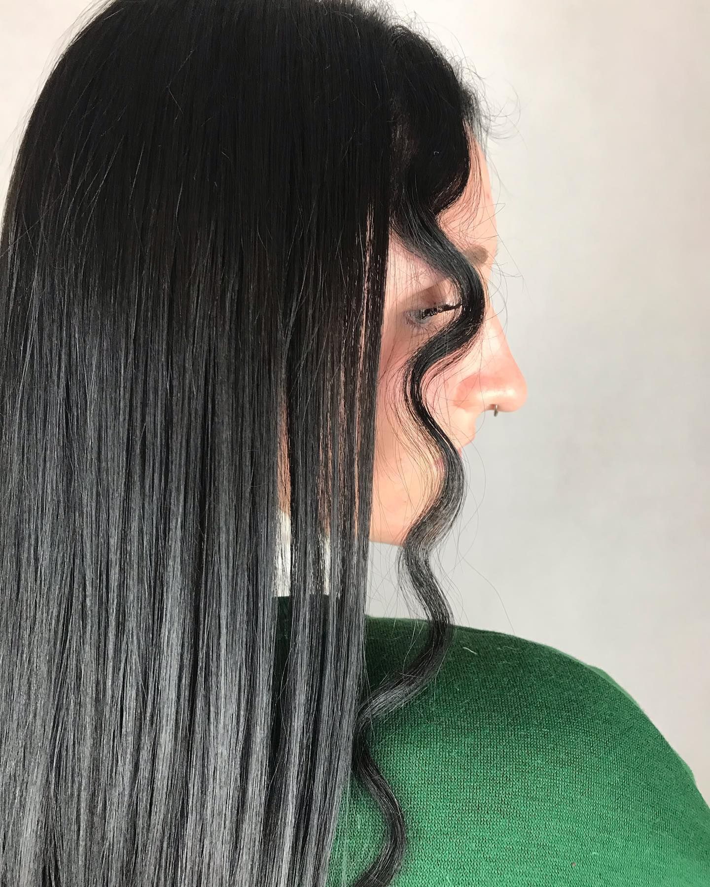Una donna con lunghi capelli neri indossa un maglione verde.