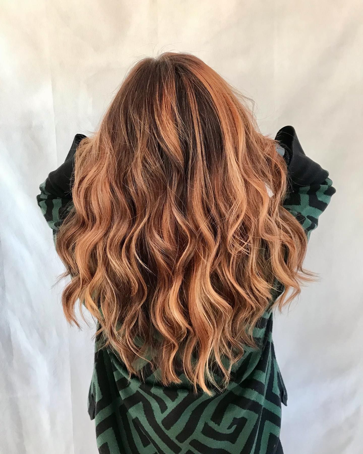 Una donna con lunghi capelli ondulati indossa una giacca verde e nera.