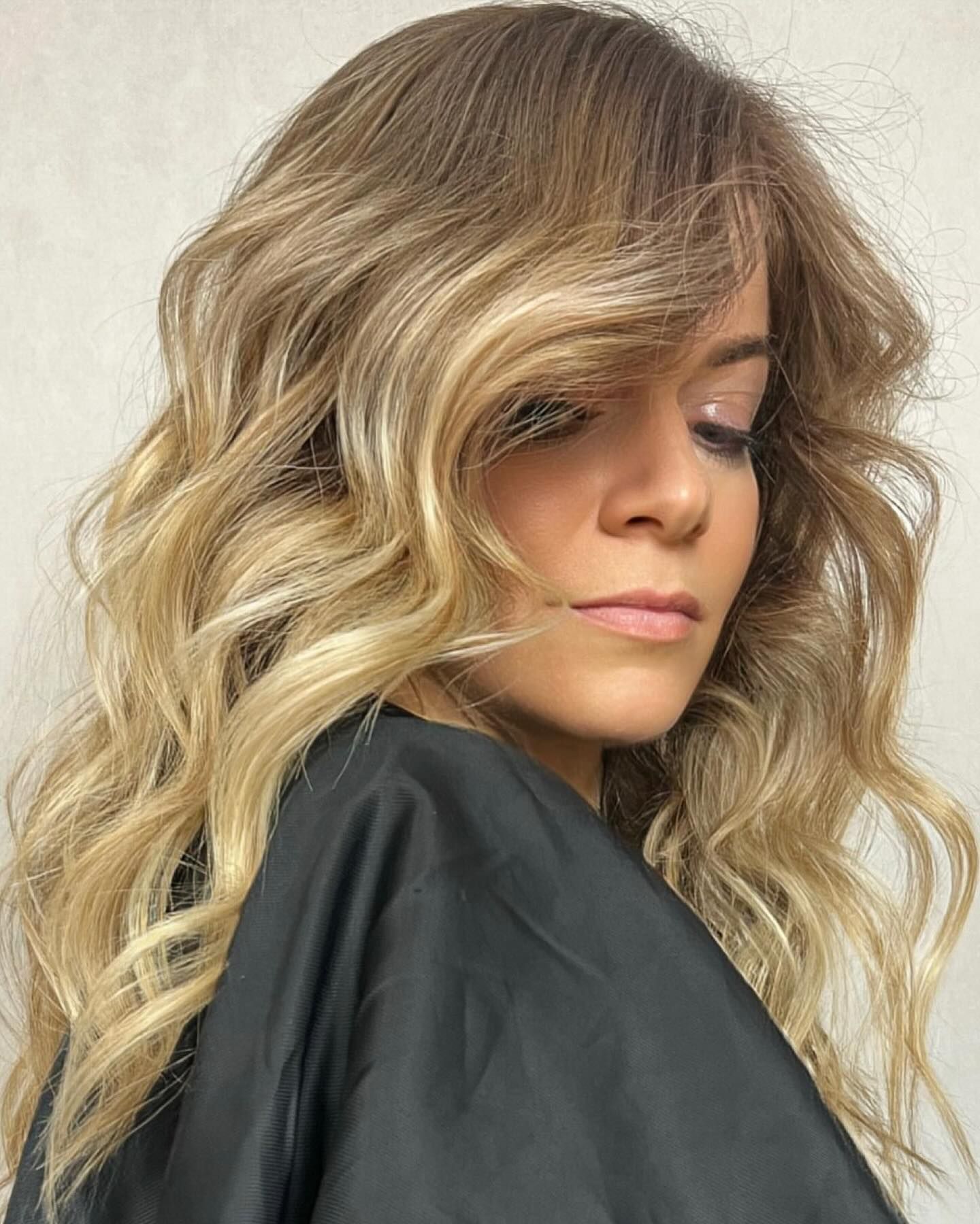 Una donna con lunghi capelli biondi indossa un mantello nero.