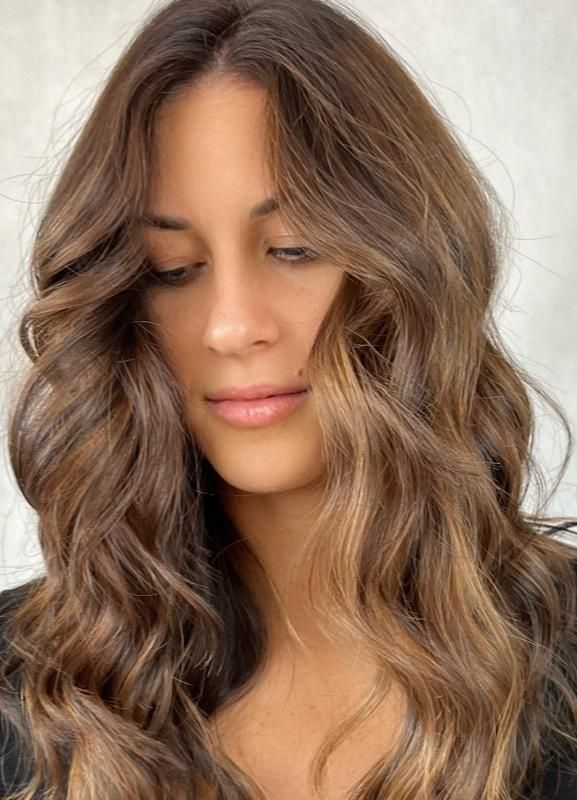 Una donna con lunghi capelli castani indossa una camicia nera.