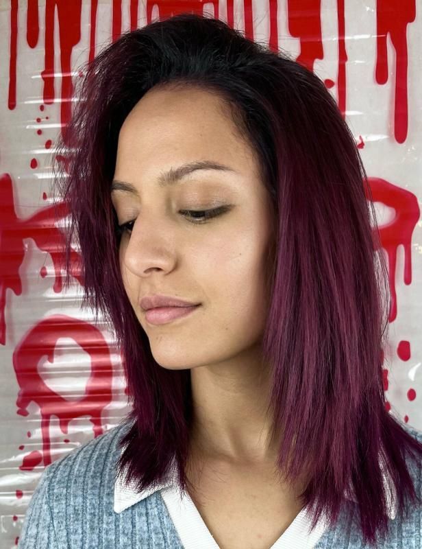 Una donna con i capelli viola indossa un maglione blu