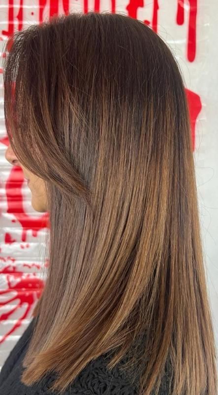 Una donna con lunghi capelli castani indossa una camicia nera.