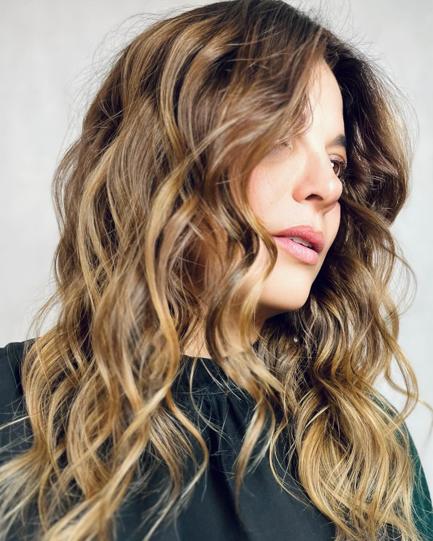 Una donna con lunghi capelli ondulati indossa una camicia nera.