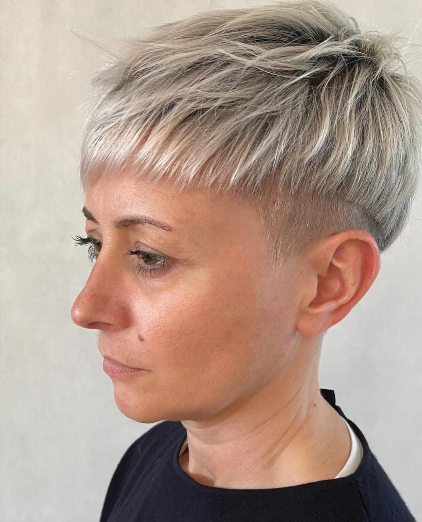 Una donna con i capelli corti e grigi indossa una maglietta nera