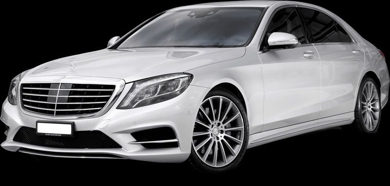 A white mercedes benz s class is parked on a black background.