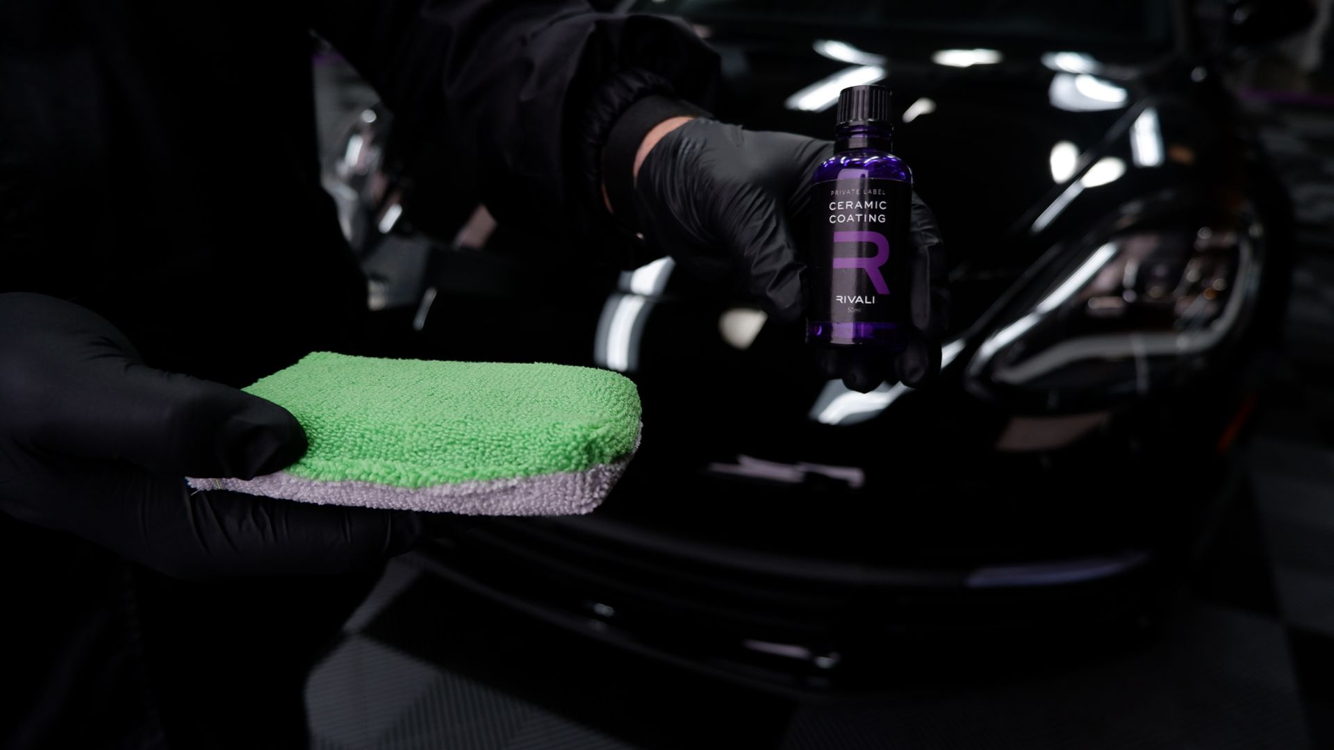 A person is cleaning a car with a green sponge.