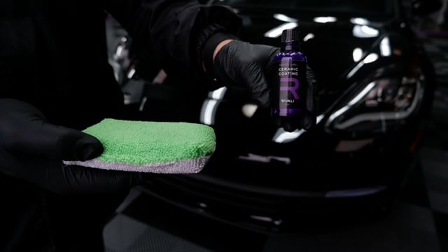 A person is cleaning a car with a green sponge.