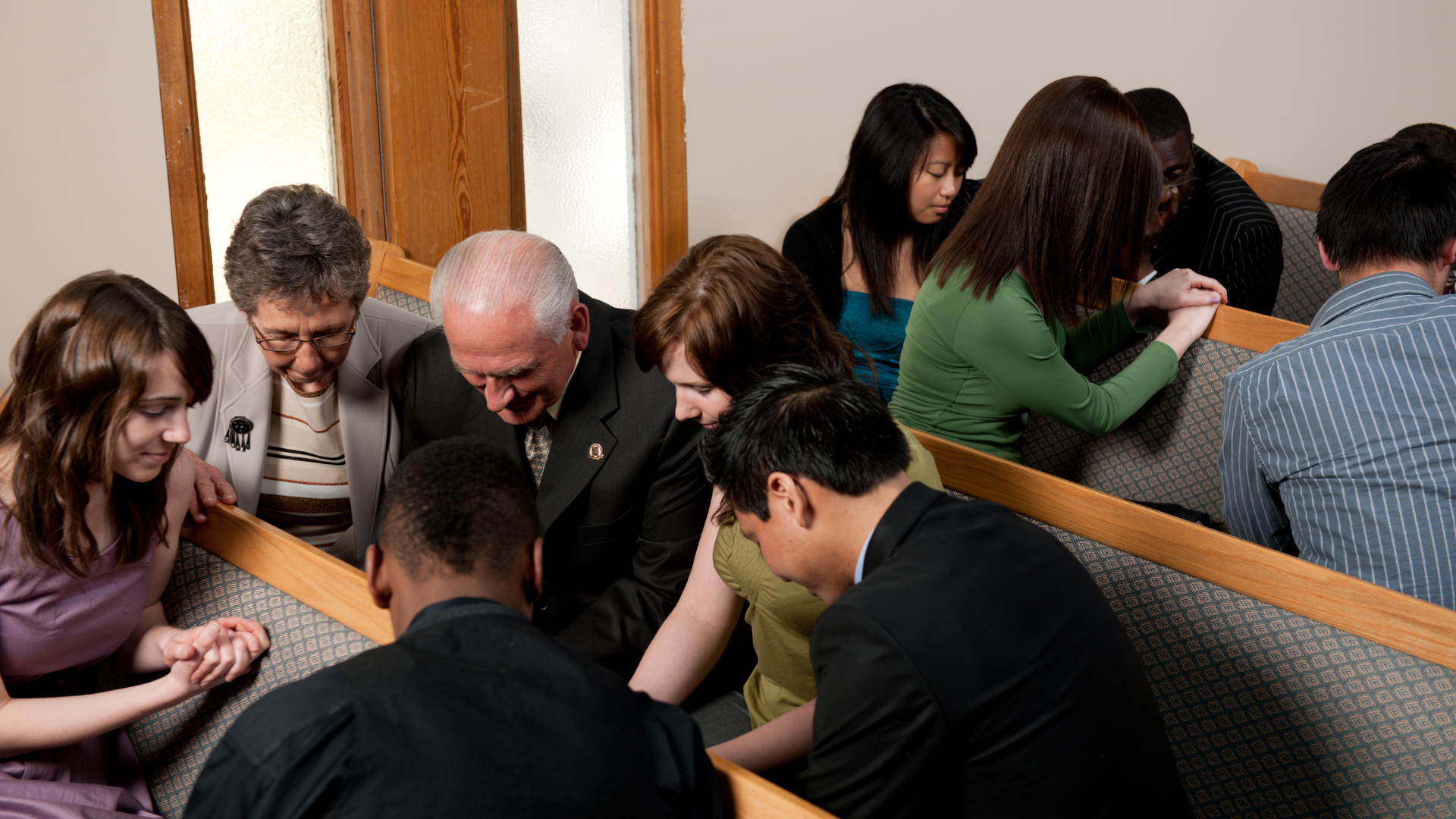 People seated closely in pews, reading and discussing together in a quiet indoor setting.