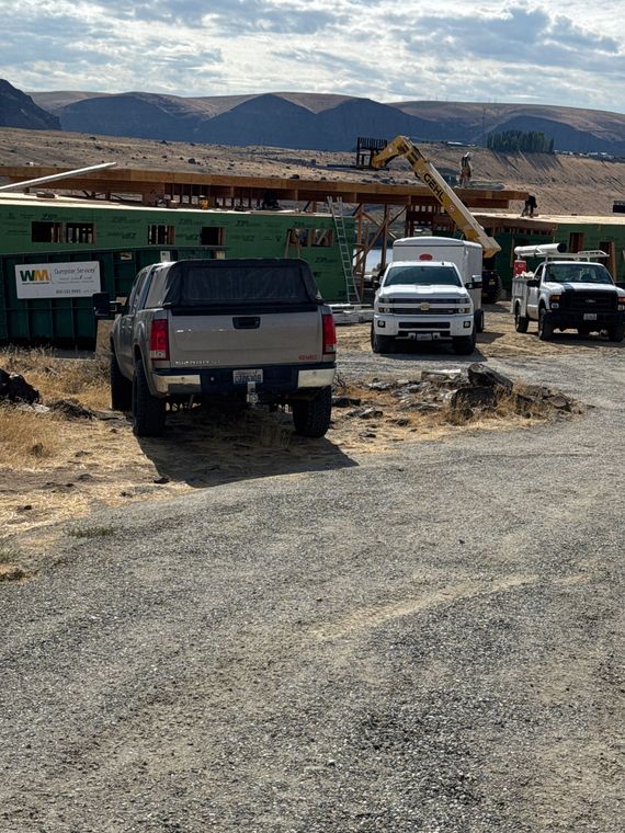 Construction site with trucks, a building in progress, and a mountain background.