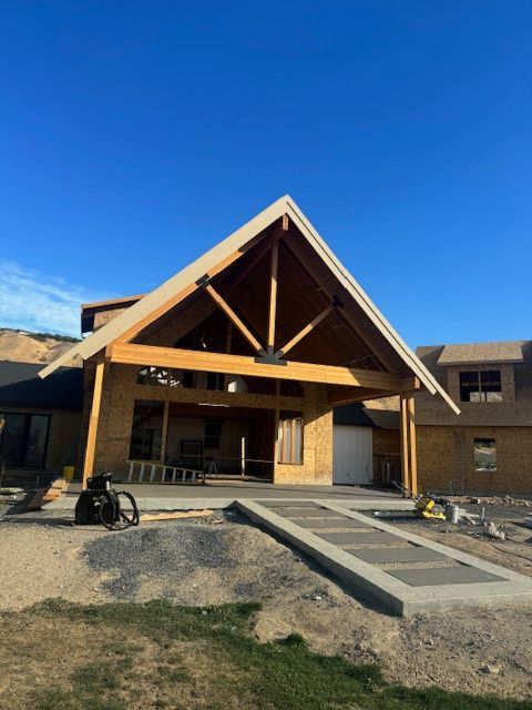 Wooden building under construction with a large porch, ramp, and blue sky.