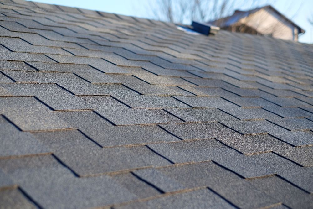 Gray asphalt shingle roof on a house with a clear sky in the background.