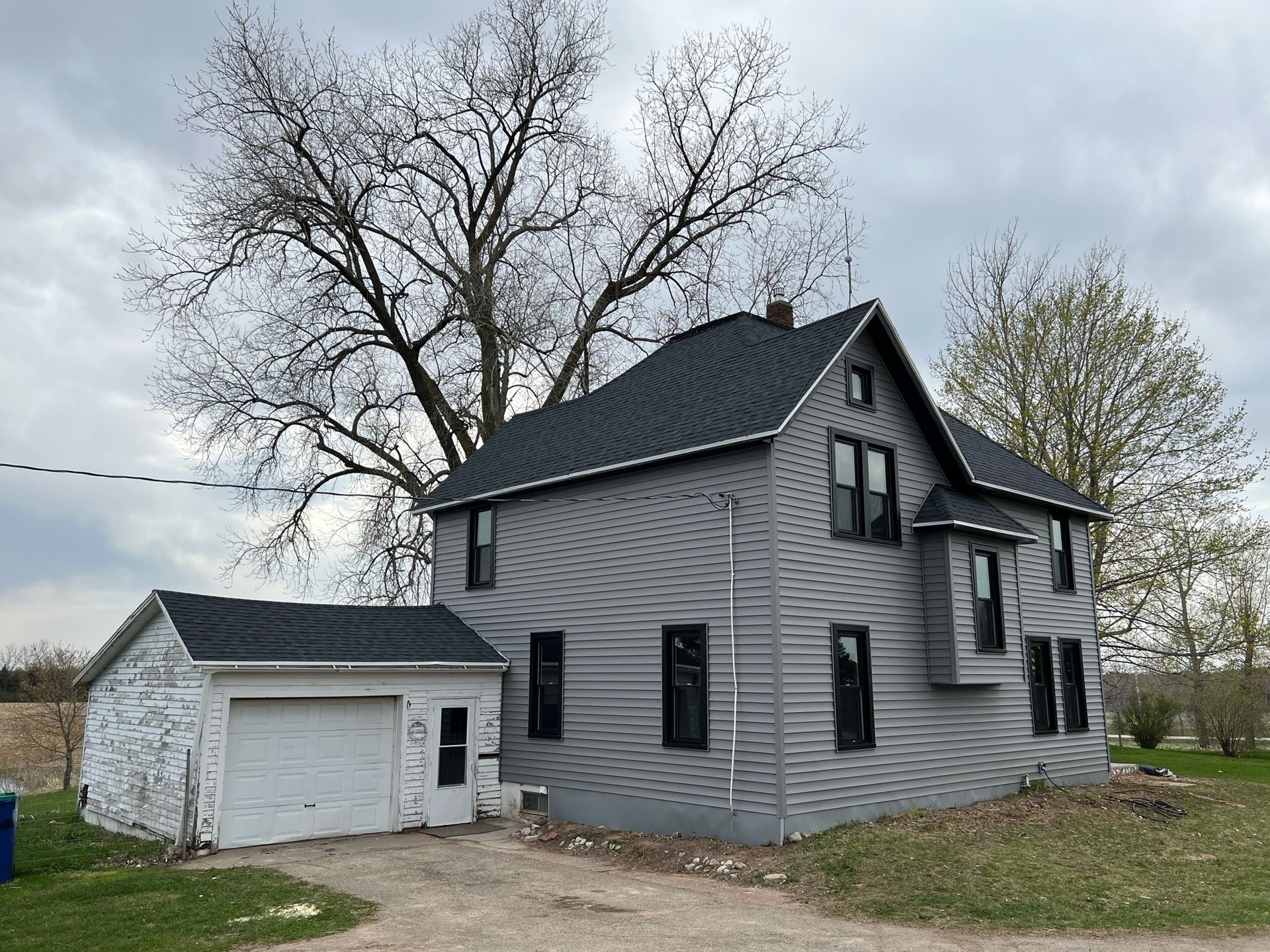 A large gray house with a black roof and a white garage.