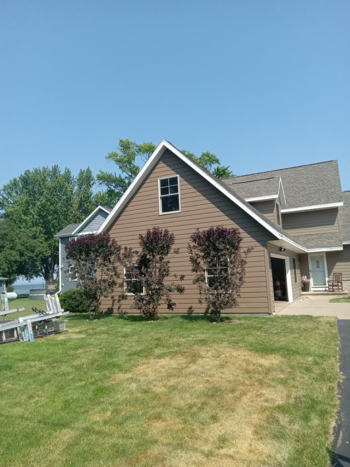 A brown house with a gray roof is sitting on top of a lush green lawn.