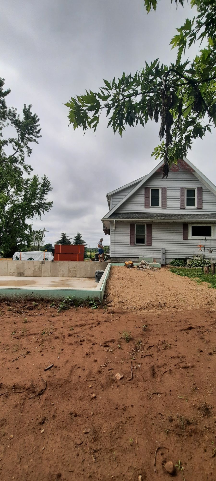 A large white house is sitting in the middle of a dirt field.