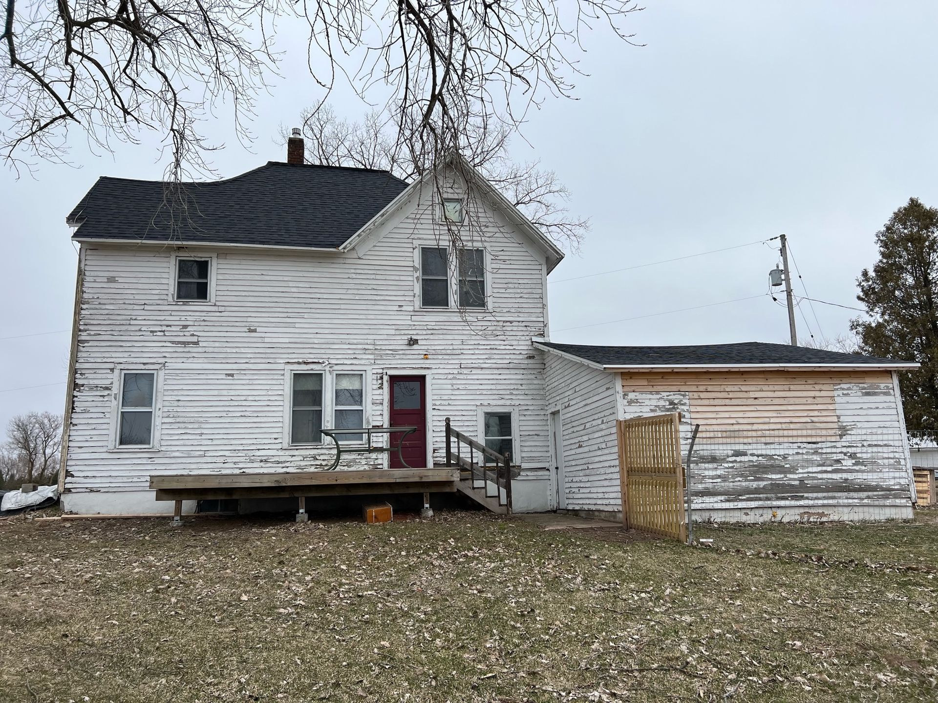 A white house with a red door is sitting in the middle of a field.