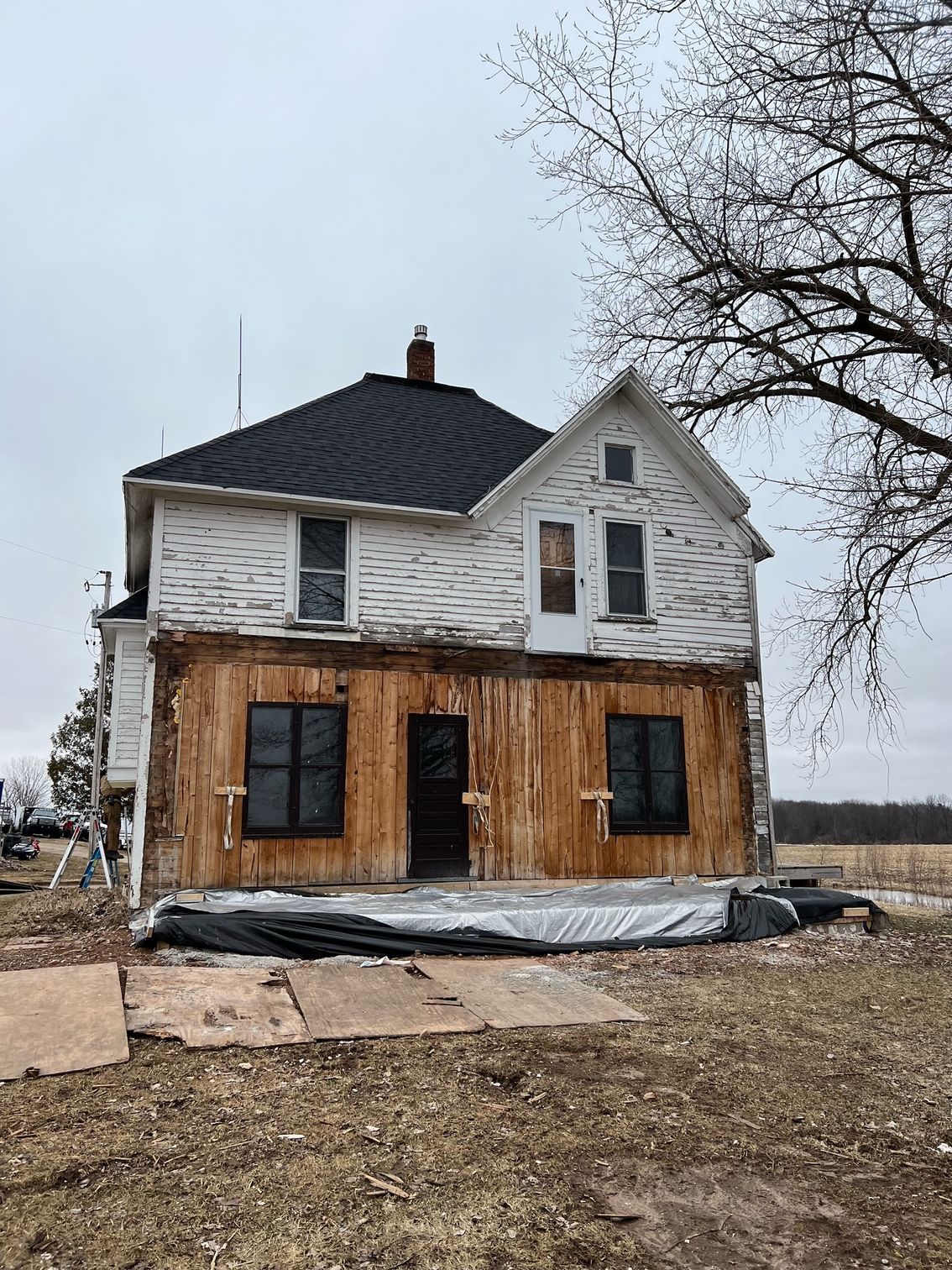 A large white house with a black roof is sitting in the middle of a field.