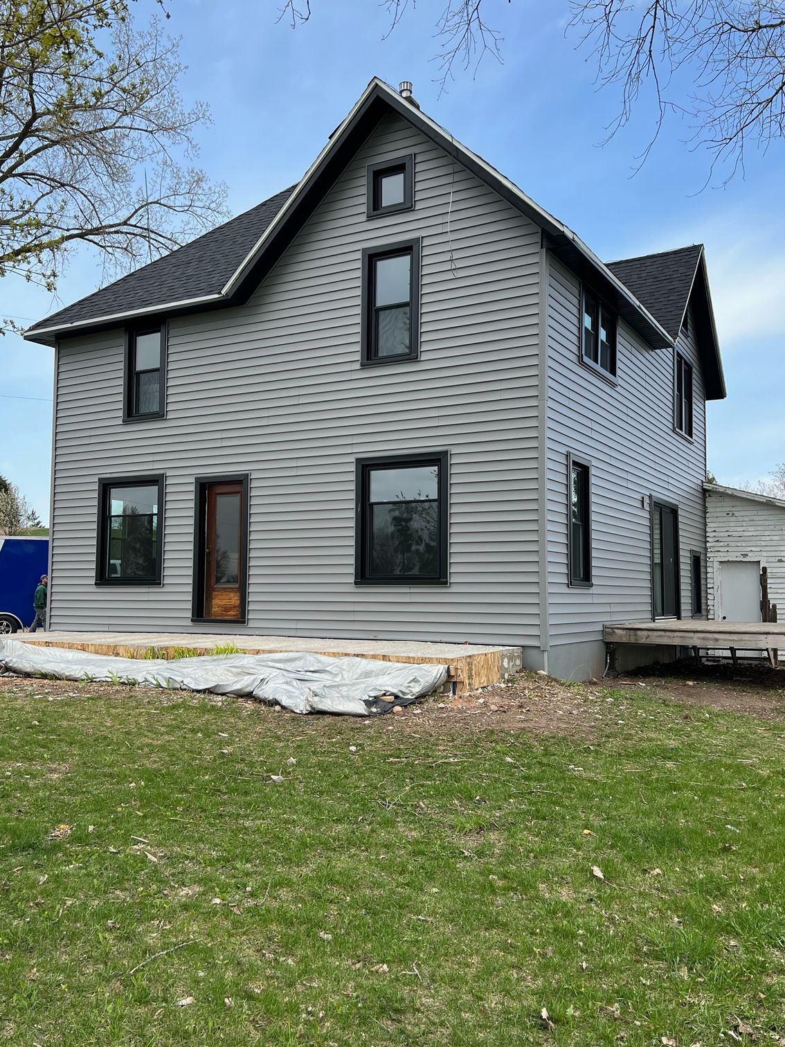 A large house with a lot of windows is sitting on top of a lush green field.