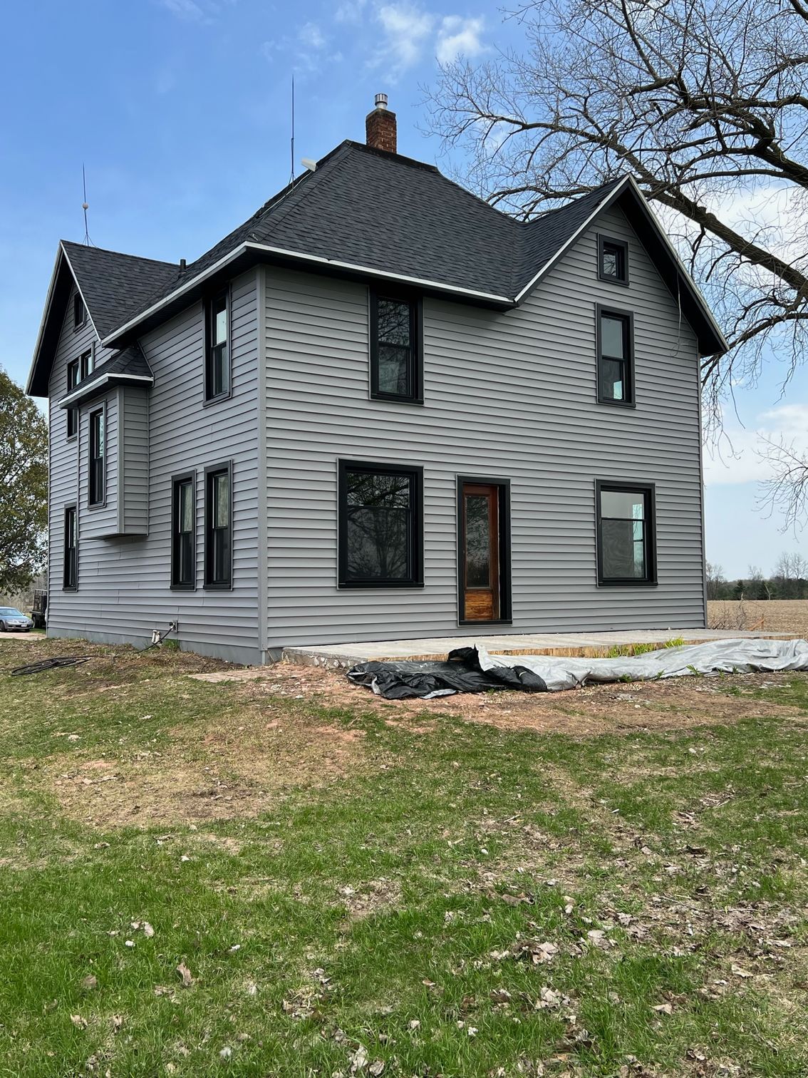 A large house with a black roof is sitting in the middle of a grassy field.