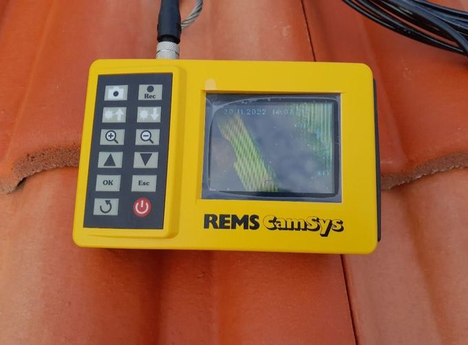 Dispositivo REIMS Sunsys giallo su un tetto di tegole rosse, che mostra un'immagine verde e gialla.