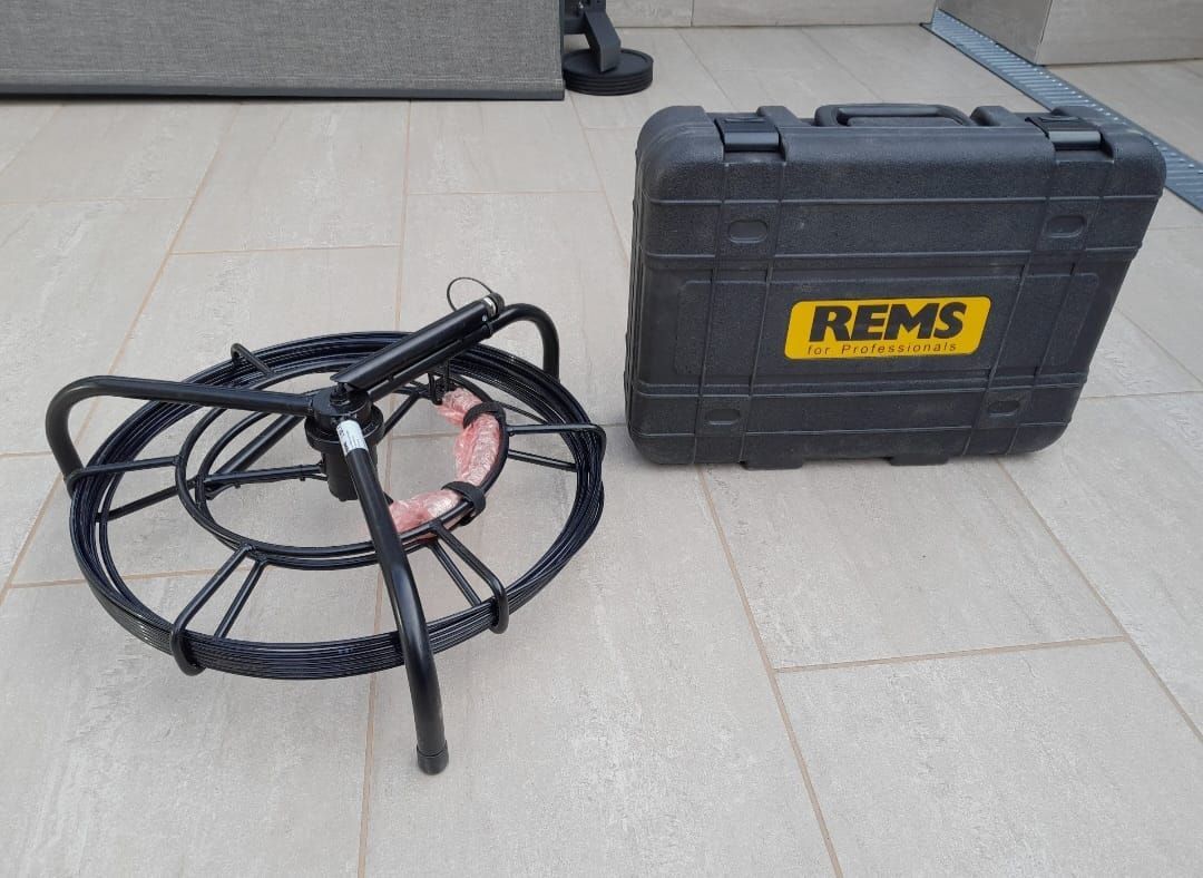 Un avvolgicavo nero e una custodia nera con testo giallo su un pavimento piastrellato.