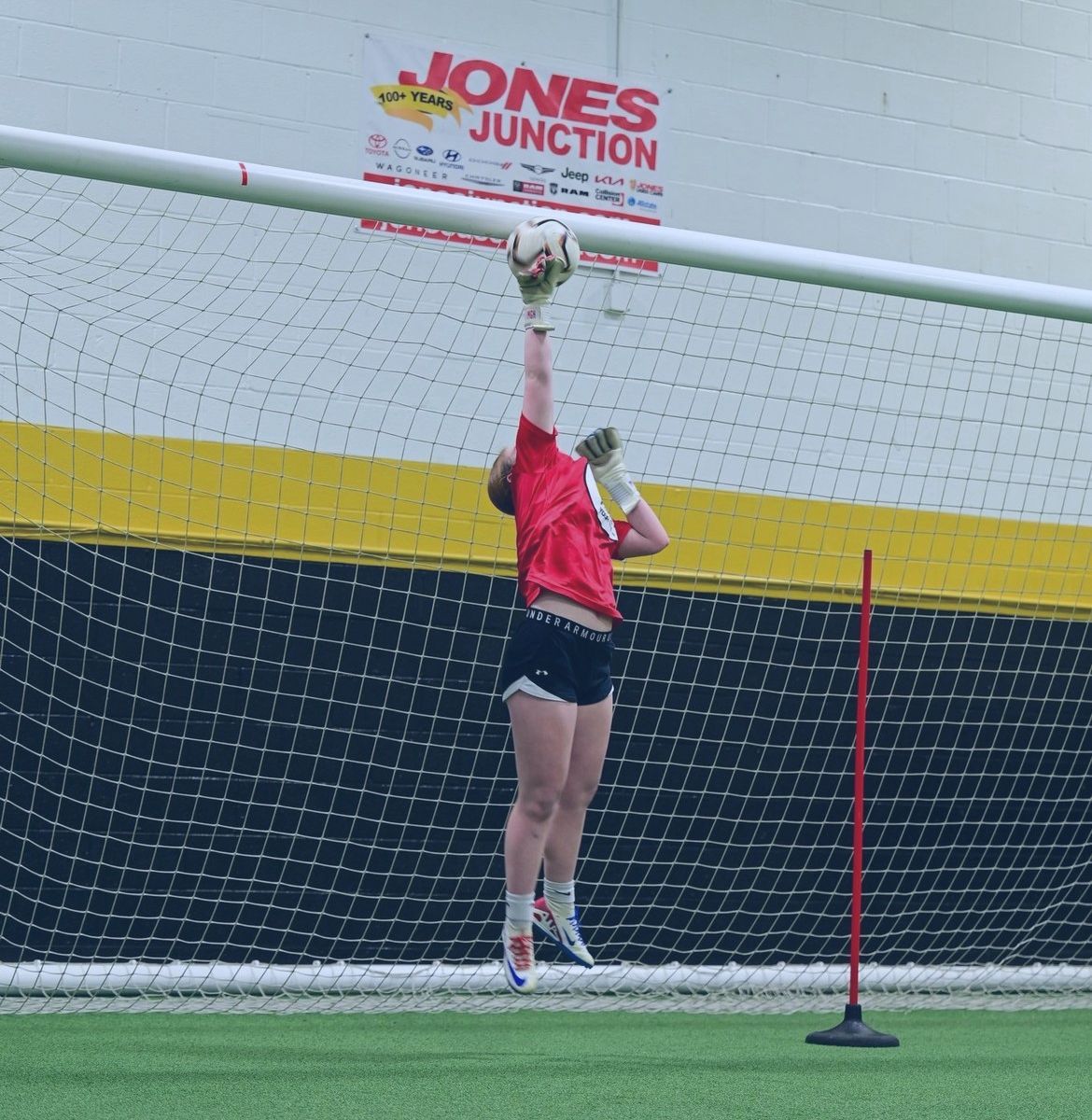 A woman catches a soccer ball in front of a jones junction sign