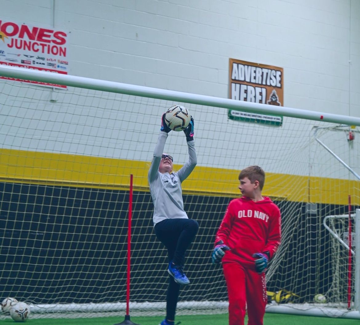 Two boys playing soccer in front of a sign that says advertise here