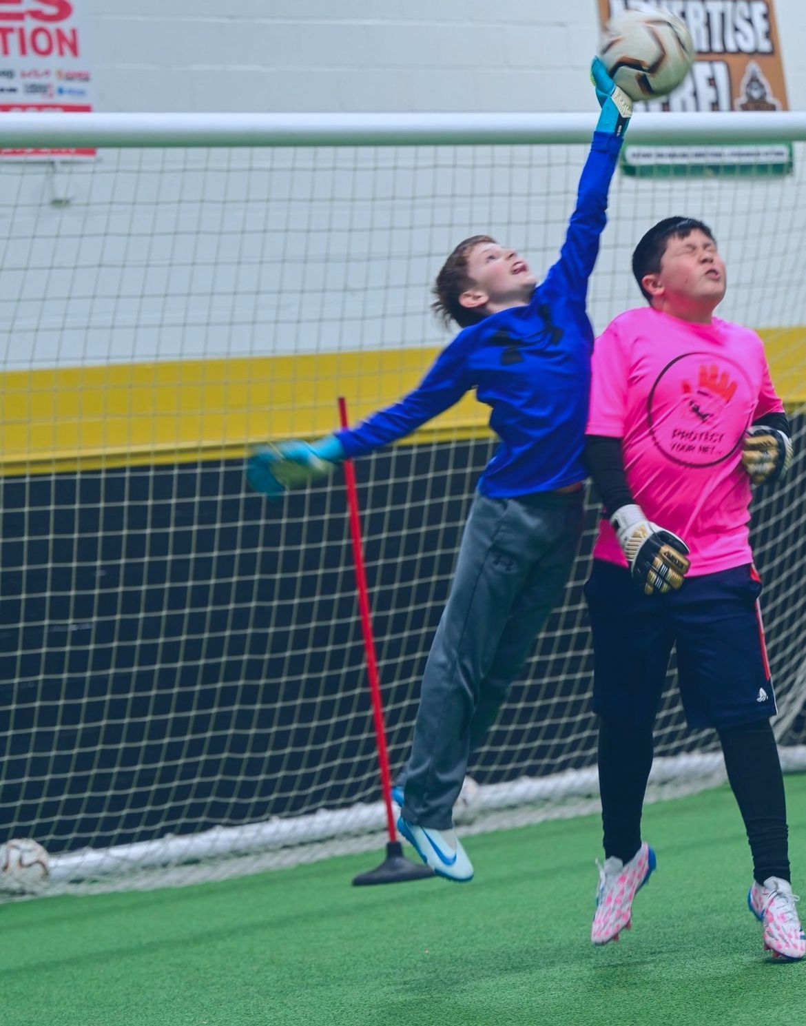 A boy in a blue shirt is catching a soccer ball