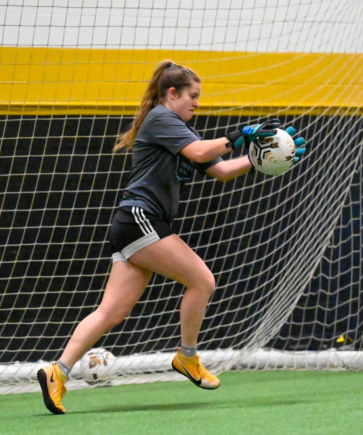 A woman is holding a soccer ball in her hands
