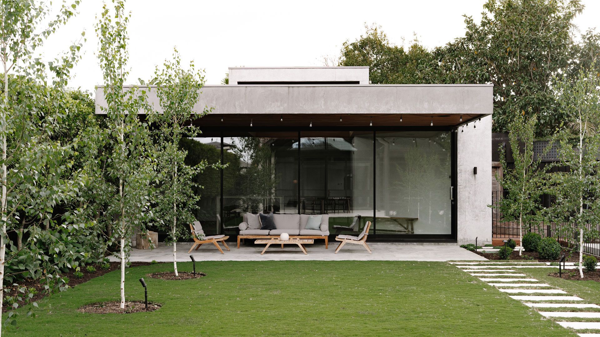 Swimming pool with turquoise water, wood deck, lounge chairs, and green trees under a blue sky.