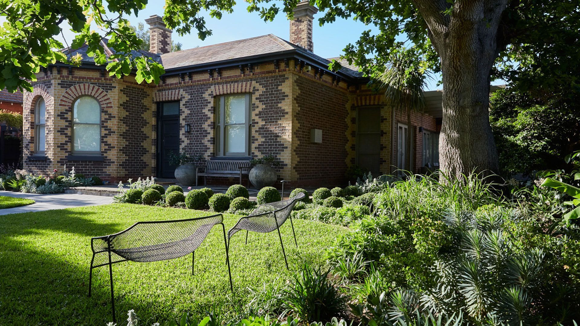 Swimming pool with turquoise water, wood deck, lounge chairs, and green trees under a blue sky.