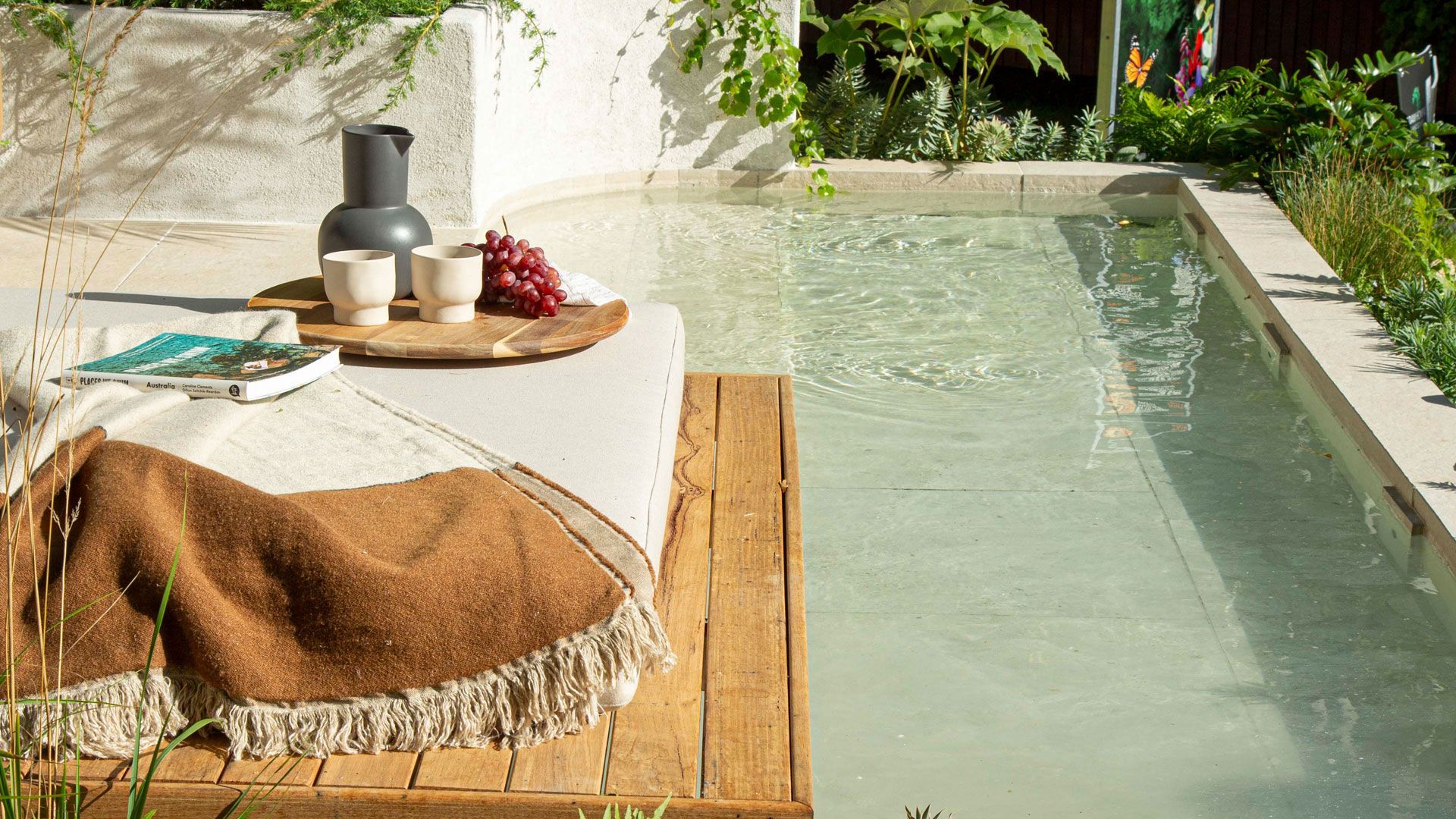 Modern home with pool, lounge area, and dark wood exterior. Sunny outdoor setting.