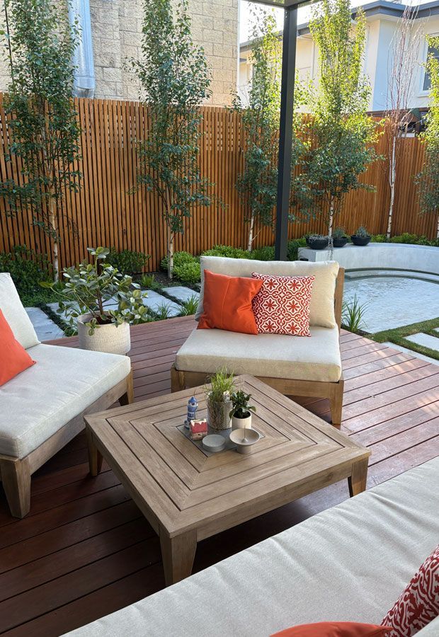 Swimming pool with turquoise water, wood deck, lounge chairs, and green trees under a blue sky.