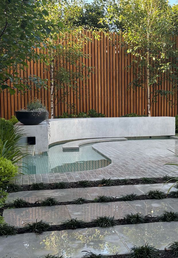 Modern home with pool, lounge area, and dark wood exterior. Sunny outdoor setting.