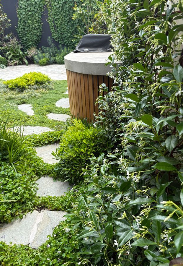 Outdoor lounge area with a pool. Features a white pergola, seating, and lush landscaping.