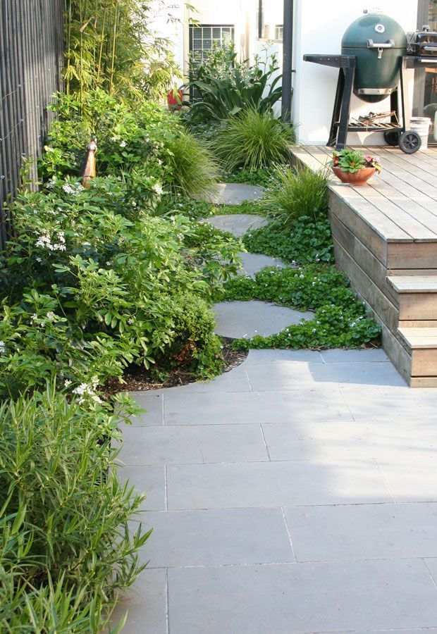 Modern house with pool, shaded patio, and wooden pergola. Turquoise water, glass walls, and dark wood siding.