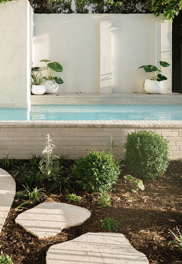 Luxury backyard pool with lounge seating under a pergola and steps leading to pool.