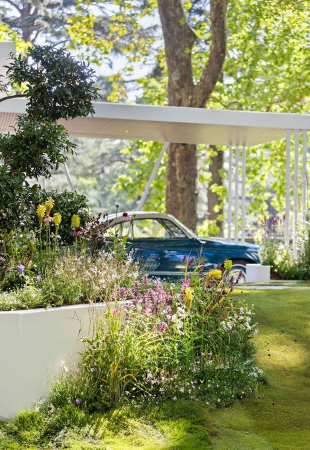 Outdoor lounge area with a pool. Features a white pergola, seating, and lush landscaping.