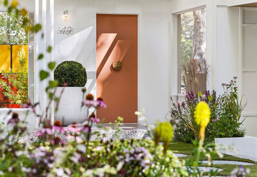 Modern home with pool, lounge area, and dark wood exterior. Sunny outdoor setting.