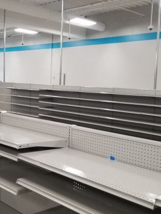 Empty shelves in a store with a blue stripe on the wall.