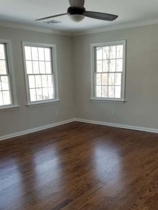 An empty room with hardwood floors and a ceiling fan.