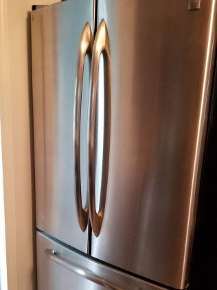 A stainless steel refrigerator with two doors is sitting in a kitchen.