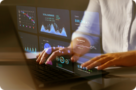 Pessoa trabalhando em um laptop com visualizações de dados sobrepostas na tela, em ambiente interno.