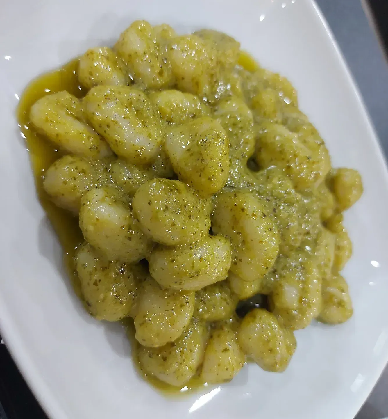 Un piatto di gnocchi al pesto su un tavolo.