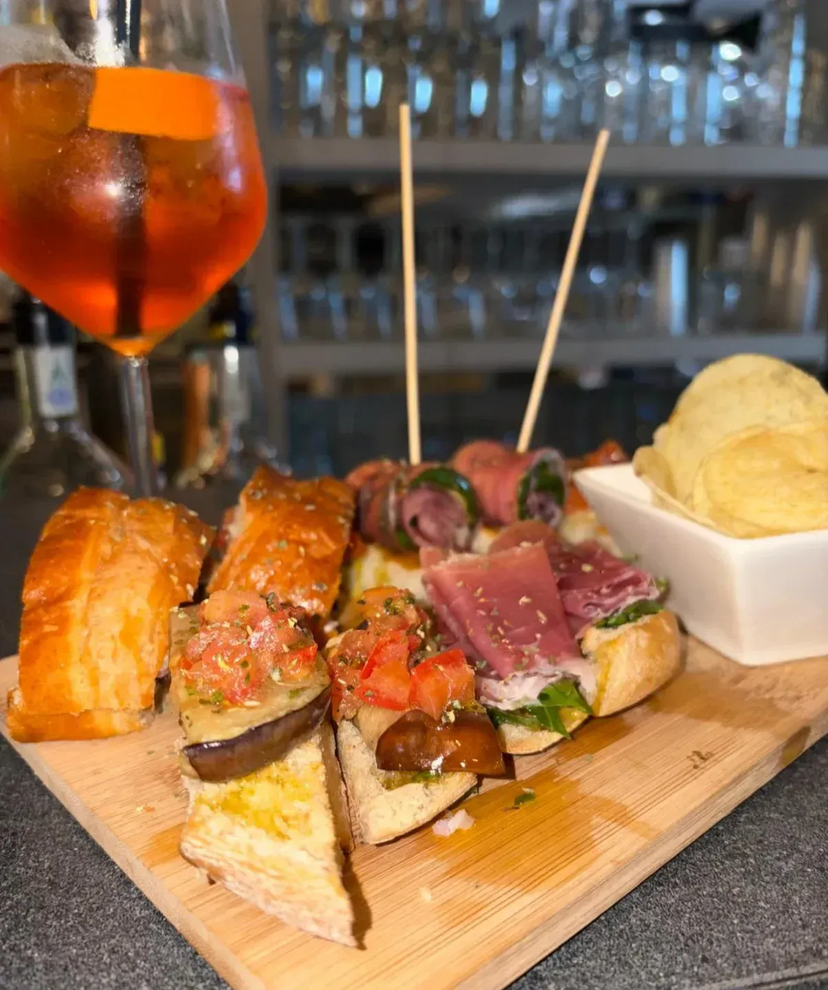 Un tagliere di legno sul quale sono disposti vari alimenti e un bicchiere di vino.